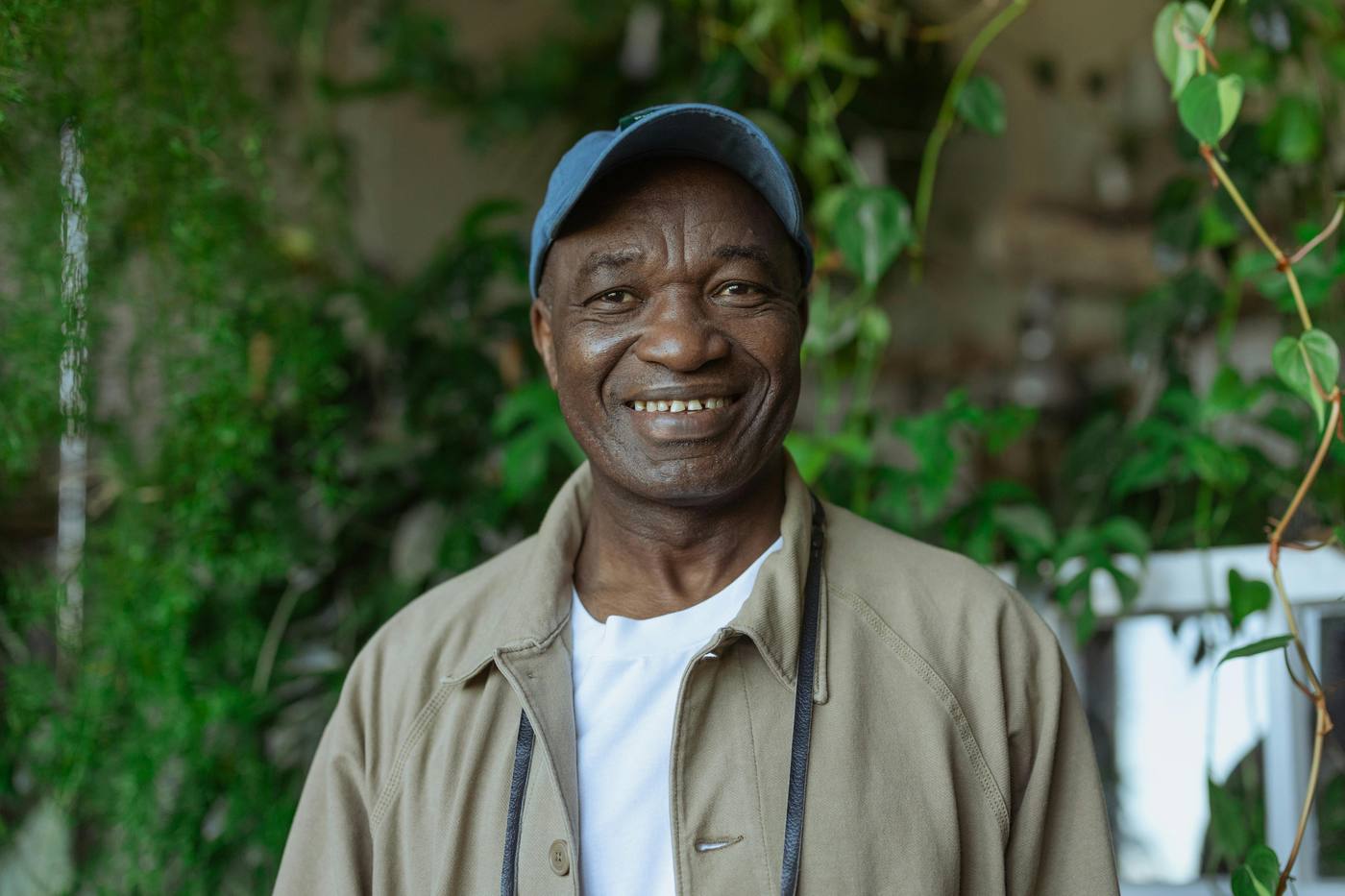 A man smiling warmly surrounded by greenery